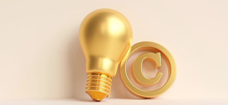 A golden light bulb leaning against a copyright symbol to show how copyright protection supports AI innovation
