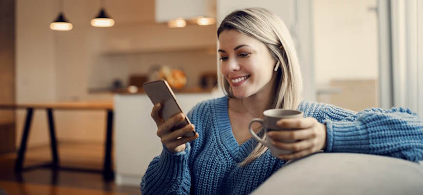 -happy woman looking at phone while enjoying coffee to show audience retention-