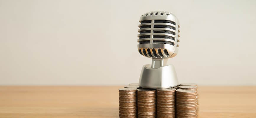 -old fashioned microphone on top of coins to suggest podcast revenue growth-