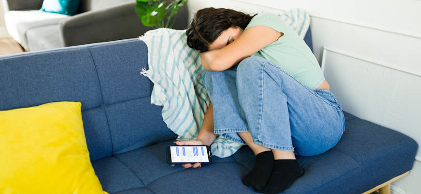 -depressed teen holding phone to suggest the need for social media regulation-