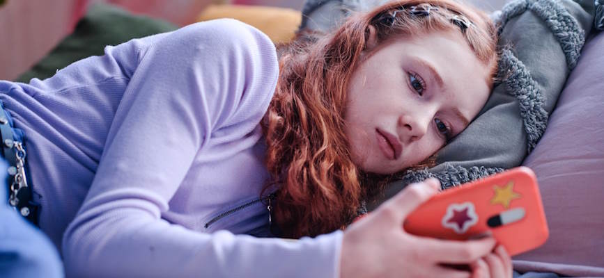 -teen girl staring unhappily at phone to show distrust in news-