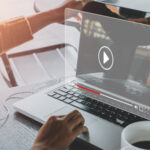 photo of a laptop being opened by hands with a holographic video player floating in front of the blank display.