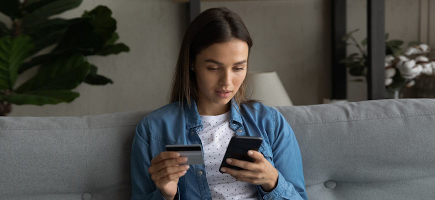 young person looking at phone with credit card out to suggest that young audiences will pay for news